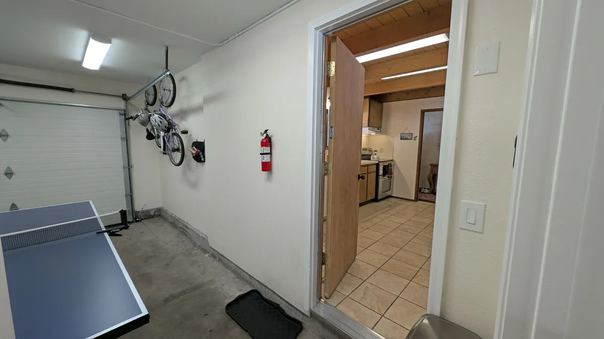 This image features bikes mounted on the wall near an open kitchen and a ping pong table, reinforcing an active, adventure-ready atmosphere. The open doorway hints at easy transitions from relaxing indoors to heading outside for exploration.