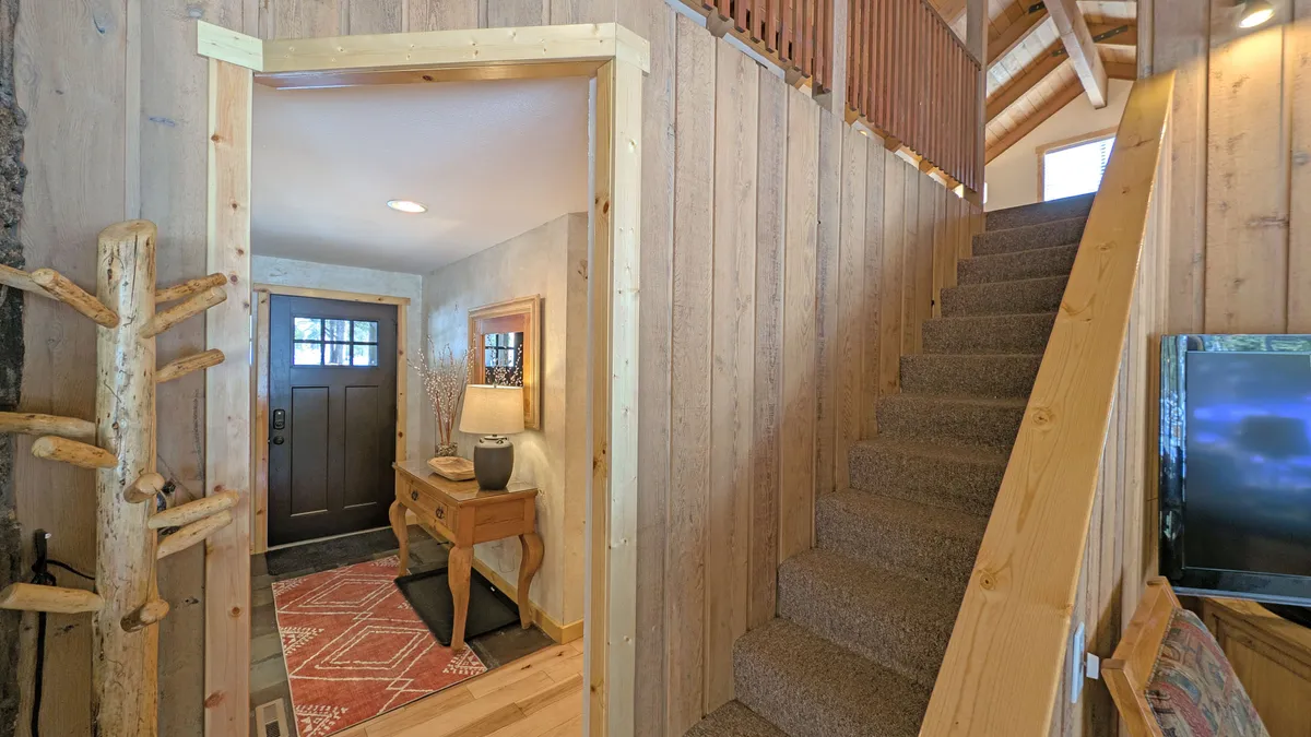 This image shows the home's inviting entrance, featuring a front door, a stylish console table with a lamp, a welcoming rug, and a staircase leading upwards. The design elements and warm lighting create an immediate sense of comfort and hospitality, suggesting a well-cared-for space that sets the tone for a relaxing stay.
