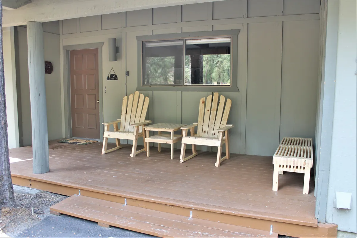 An inviting front porch with Adirondack chairs, a coffee table, and bench seating, all set near the front door, presenting a welcoming and social outdoor space.