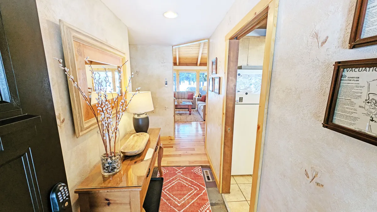A view of the home’s entryway with a wooden console, lamp, decorative branches, and a doorway leading further inside. The scene is cozy and inviting, setting the stage for guests to step outside into Sunriver’s adventure-rich environment.